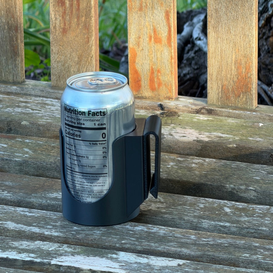 Black Can Holster on a weathered wooden bench with a silver 12 oz can seated in it, the flat clip tab visible on the side