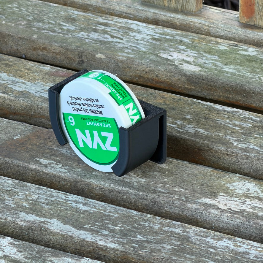 Black Pouch Holster on a weathered wooden bench, holding a green spearmint nicotine pouch can in its open slot